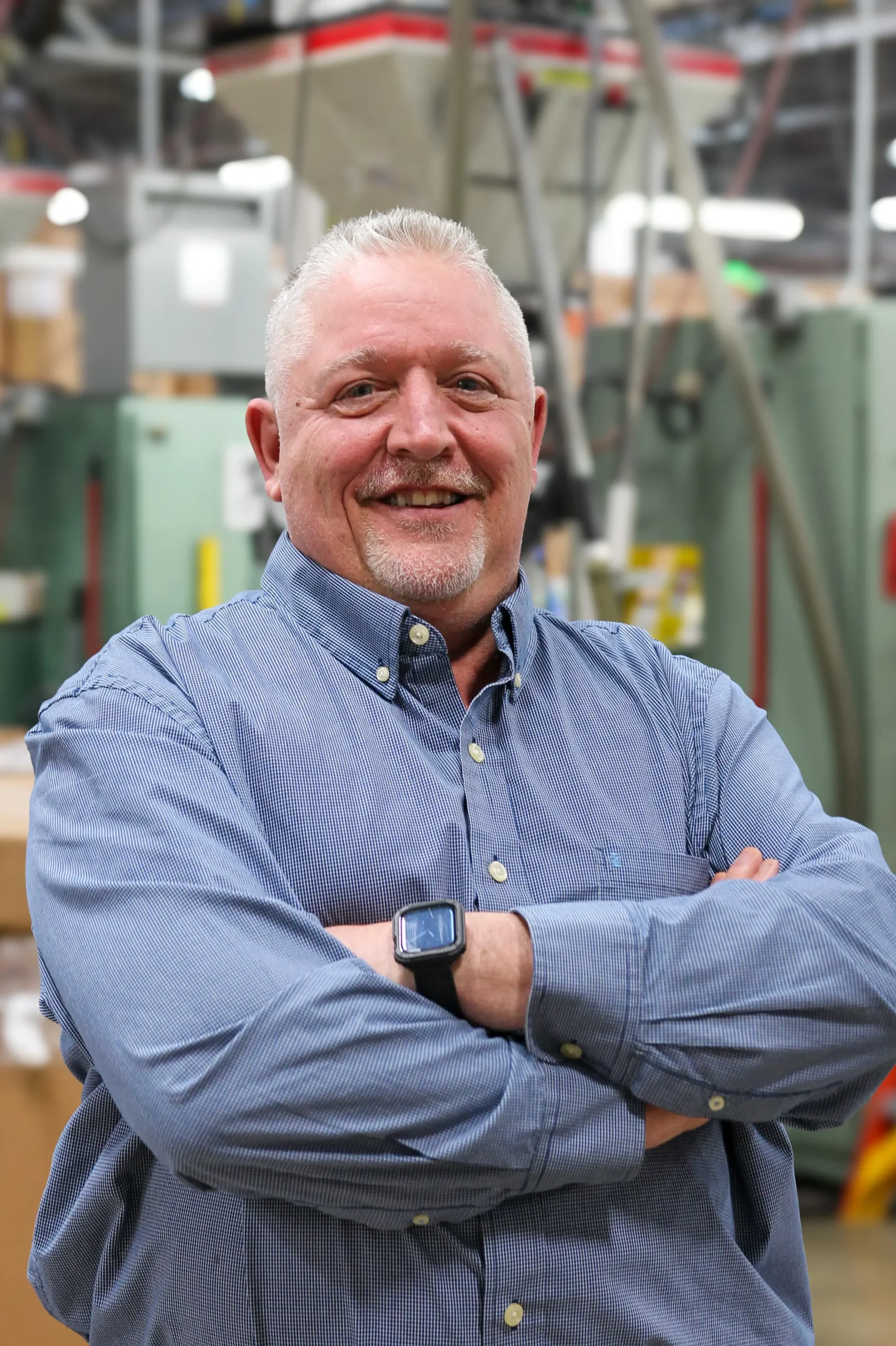 John John Danes in a blue button up long sleeve, smiling with arms crossed